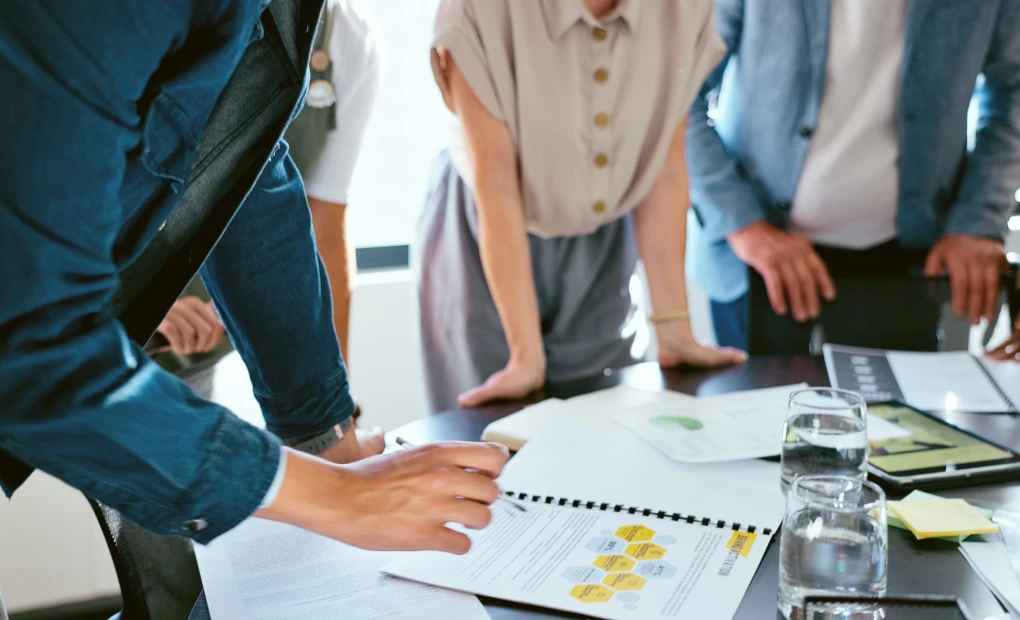 team standing around analytics printed out on desk