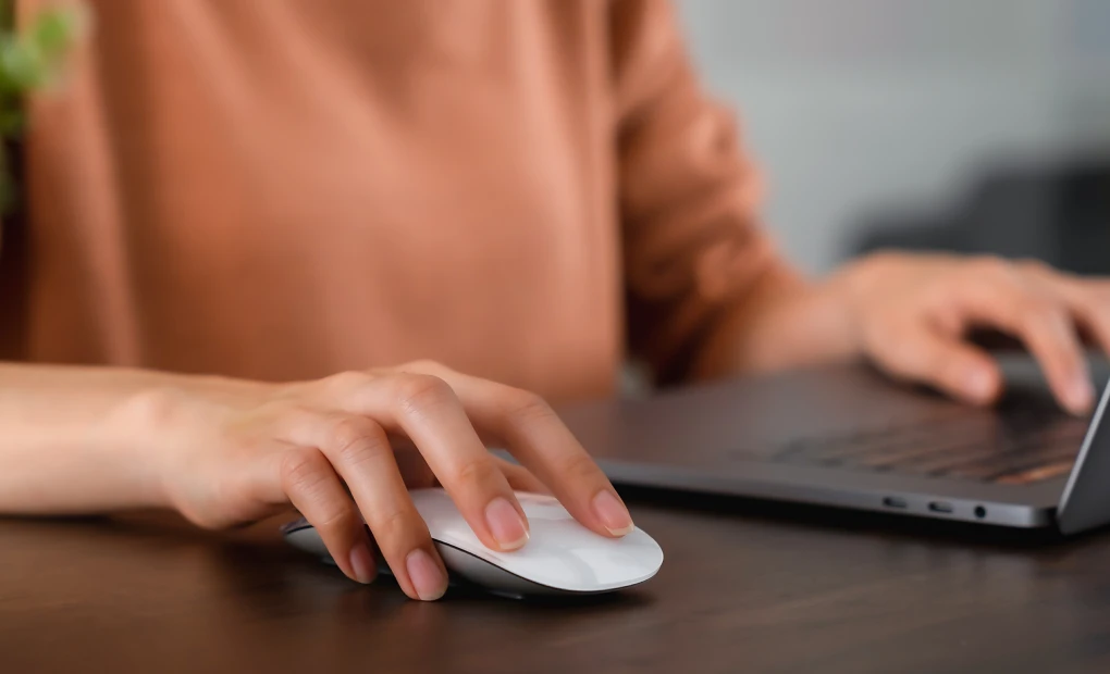 woman using mouse and typing on laptop