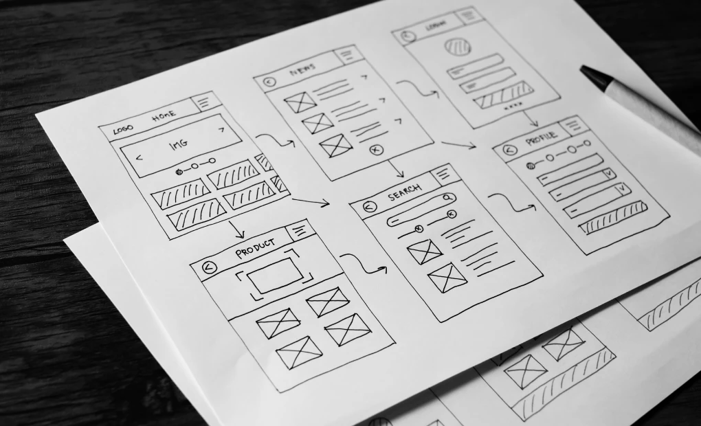 papers on desk with drawing of site wireframes